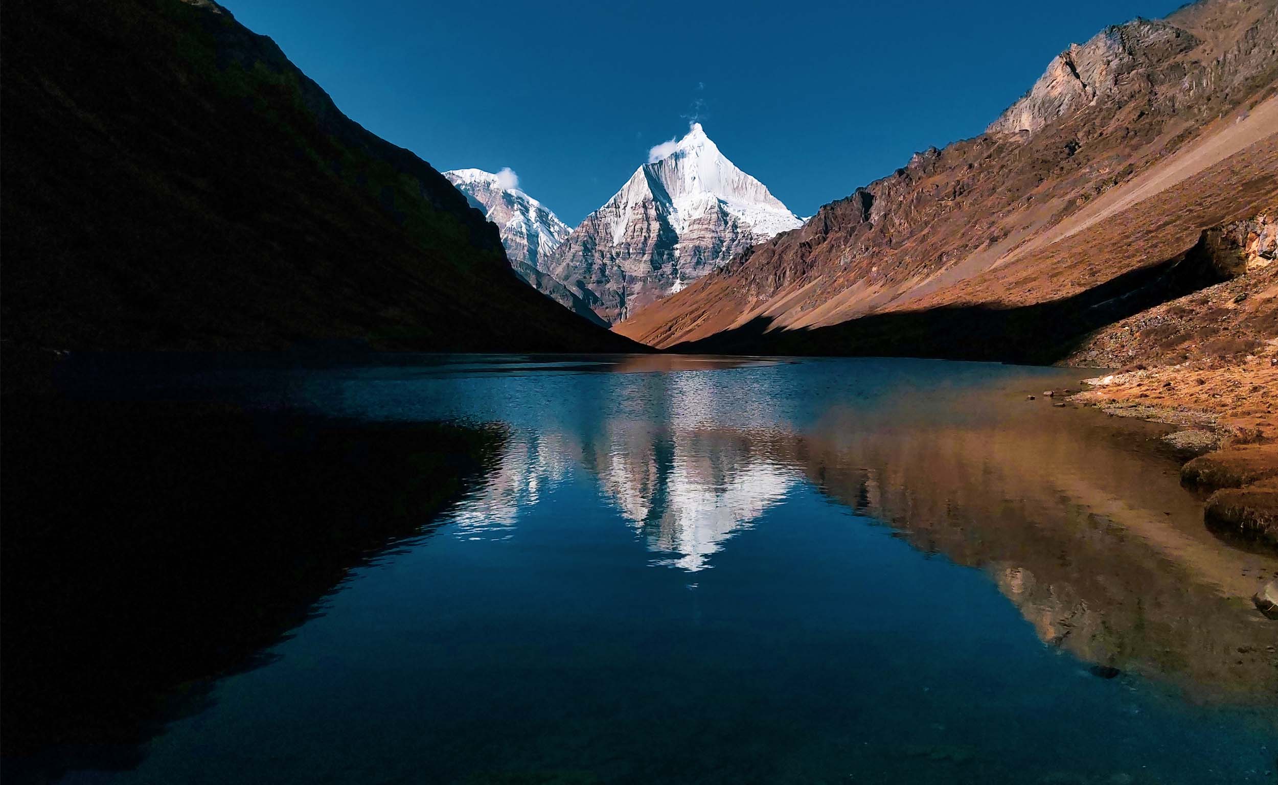 A still mountain lake mirroring Himalayan peaks