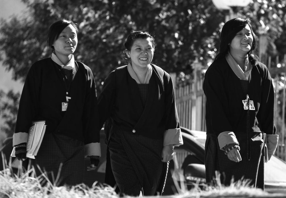 Three women in traditional kira walking together, in black and white