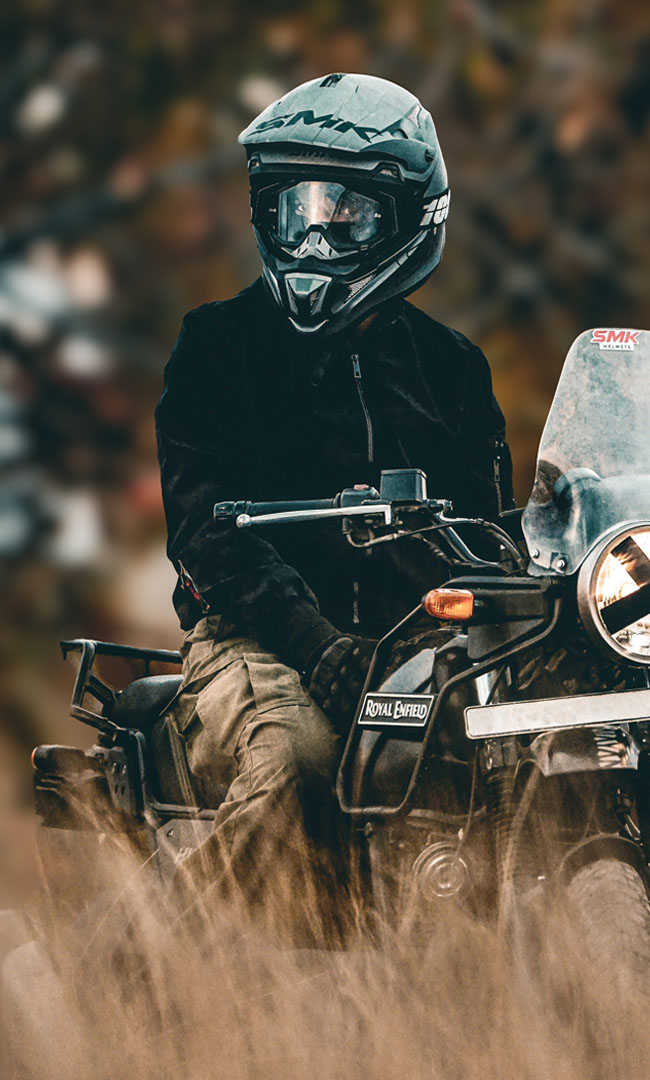 A helmeted rider on a motorbike raising dust on a country road