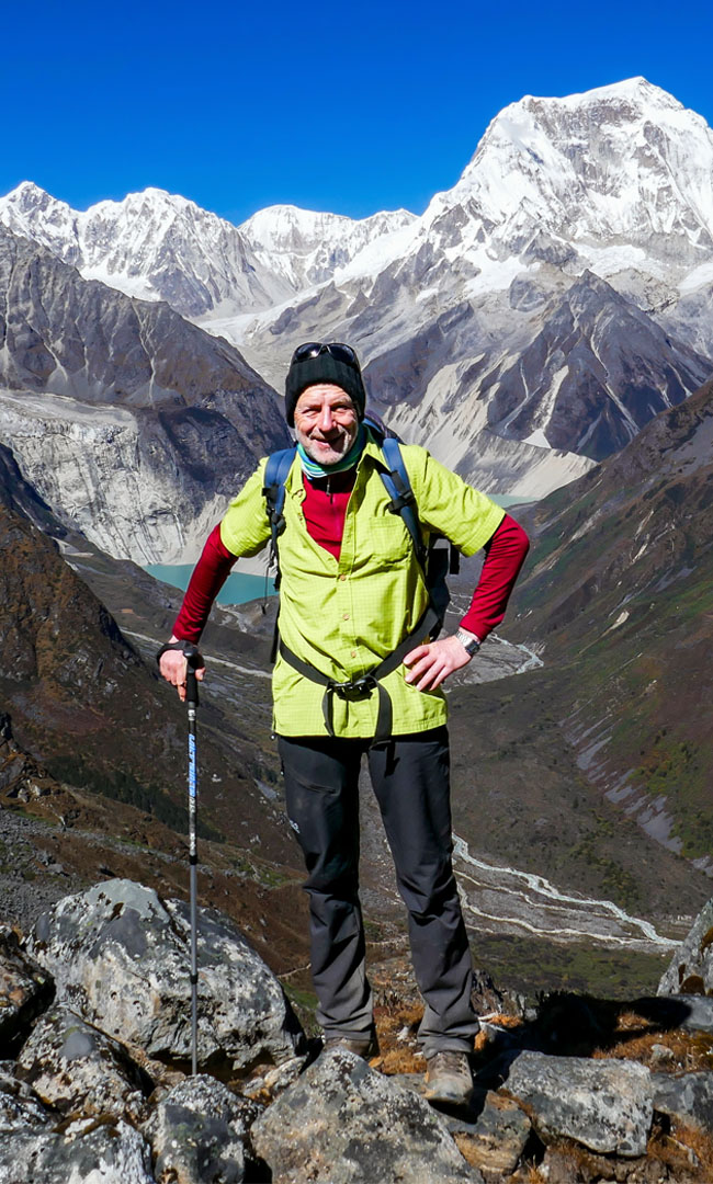 A trekker resting on a Himalayan trail below snow-capped peaks