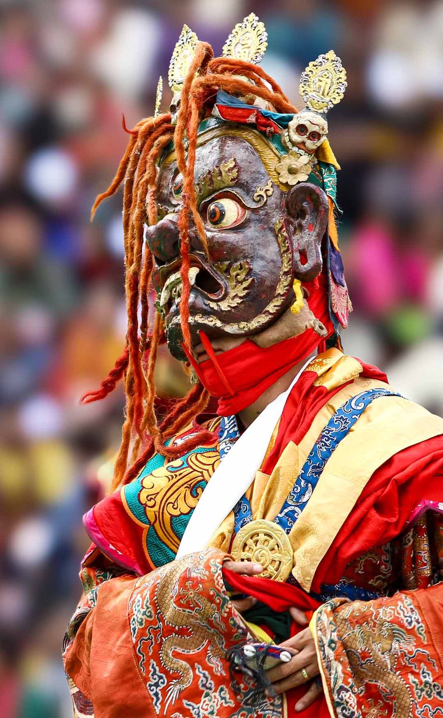 Masked dancer in brocade robes performing at a Bhutanese tsechu