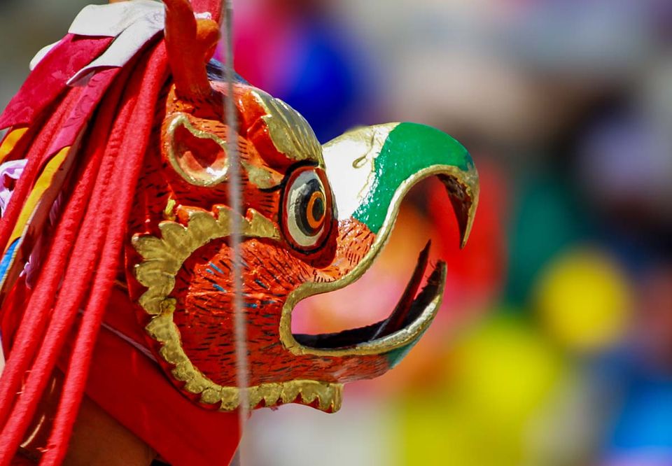 Carved bird mask in orange and green worn by a festival dancer