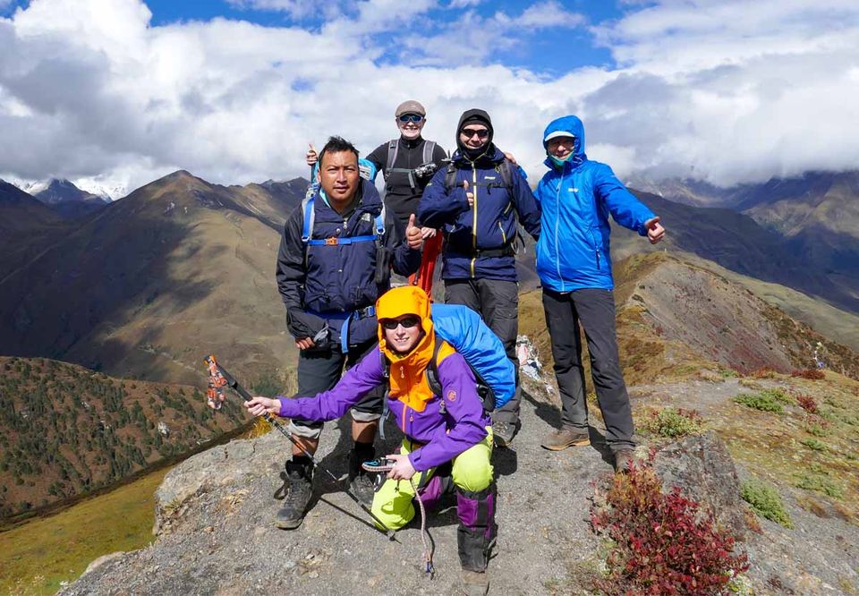 A group of hikers celebrating on a rocky ridge below the peaks