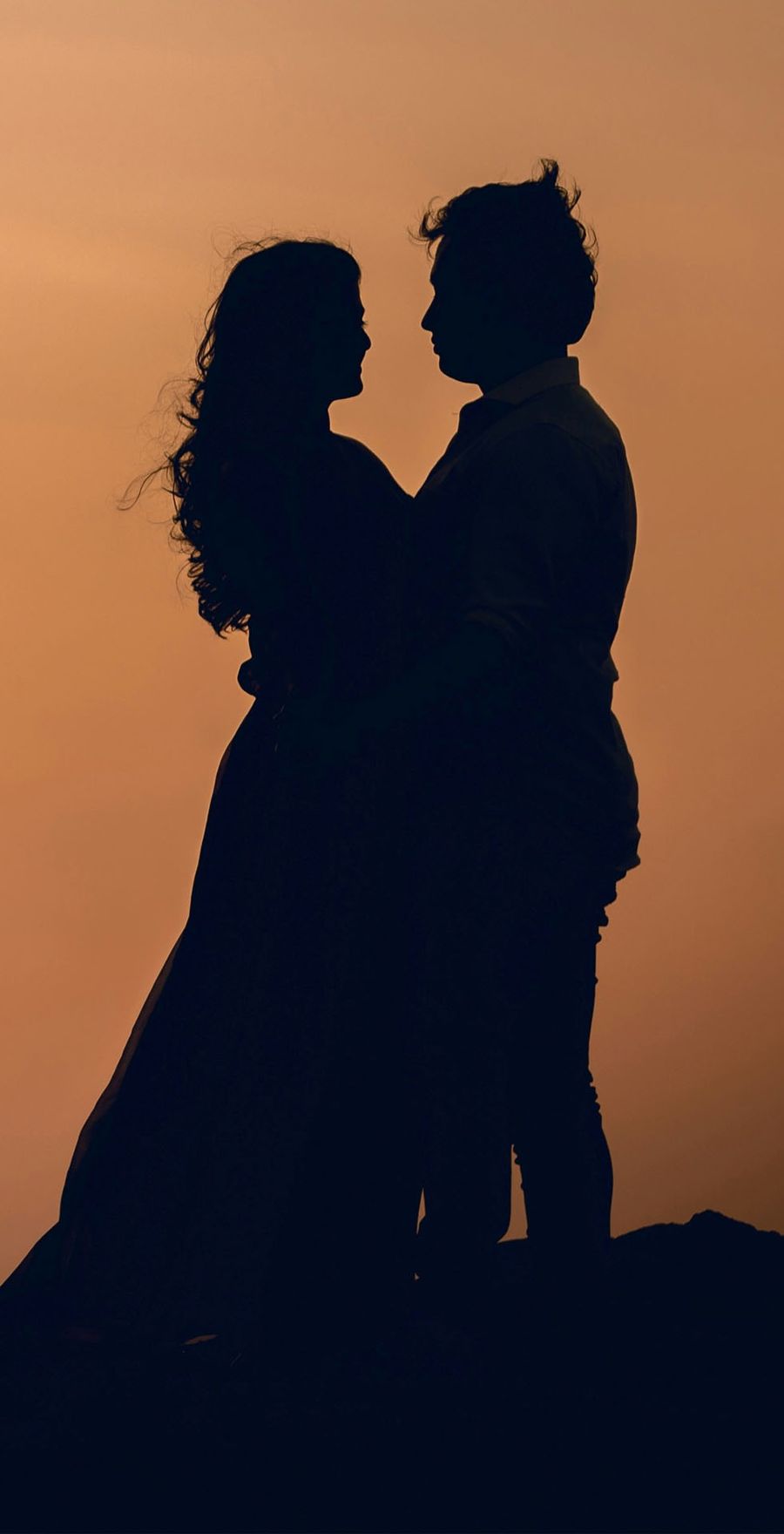 A couple silhouetted against a warm golden sky