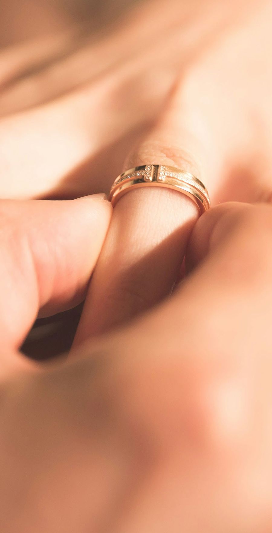 A close-up of a couple's hands wearing matching wedding bands
