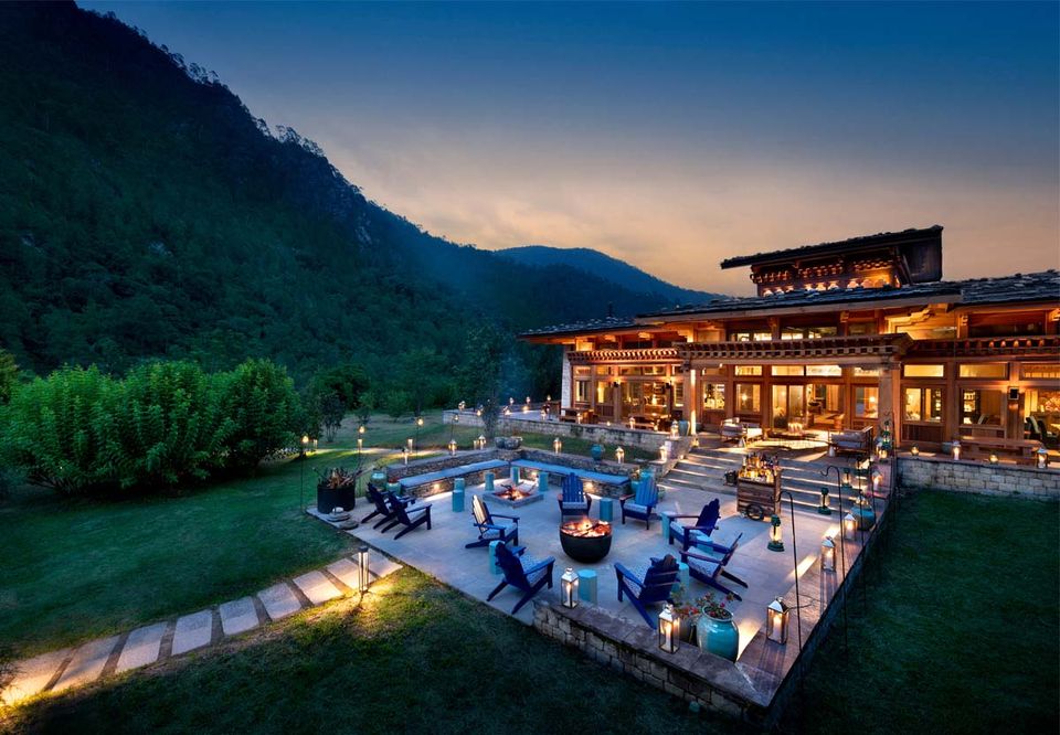 A lit resort terrace and pool above a valley at dusk