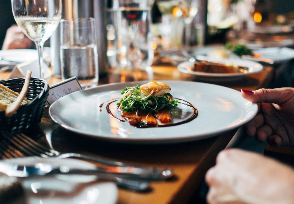 A plated tasting course served at a candlelit dining table