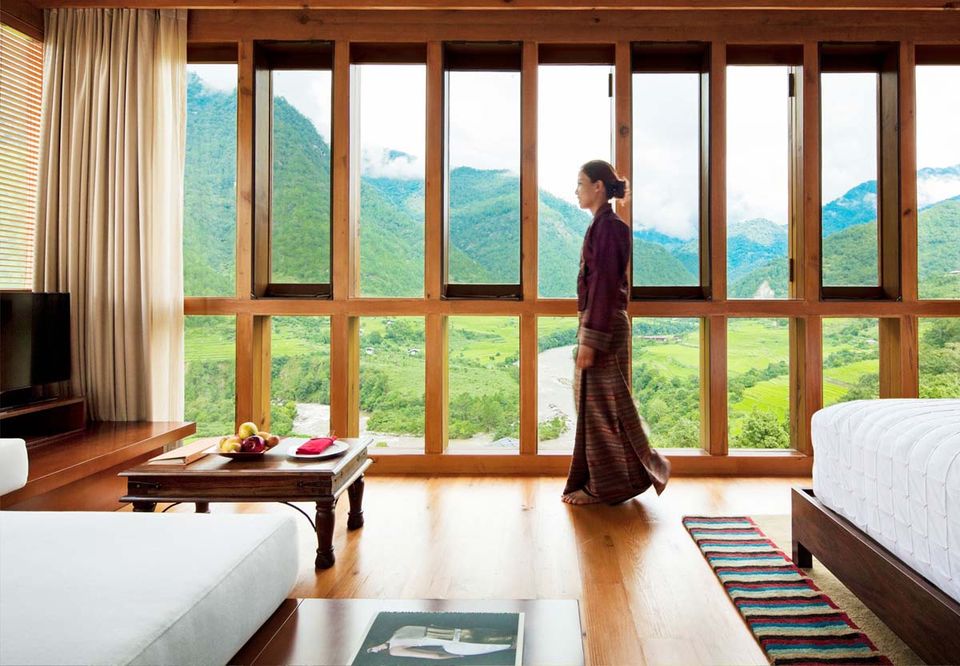 A guest in traditional dress beside floor-to-ceiling valley windows
