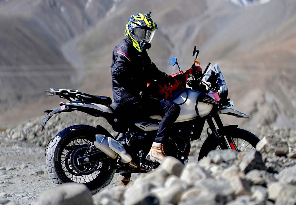 A rider standing on the pegs over a rocky riverbed