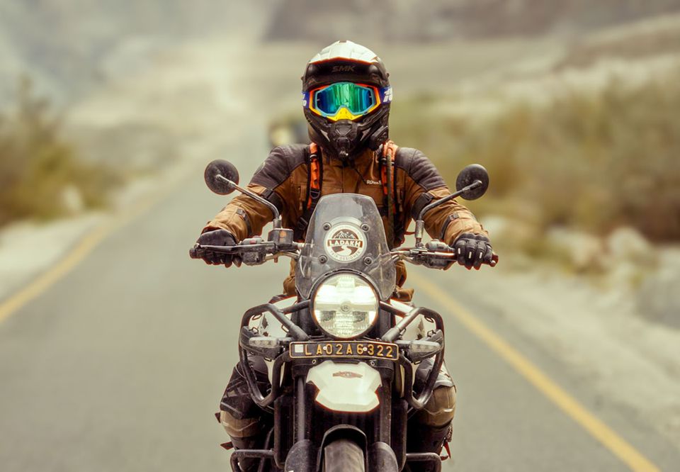 A rider in goggles head-on along an empty centre-lined highway