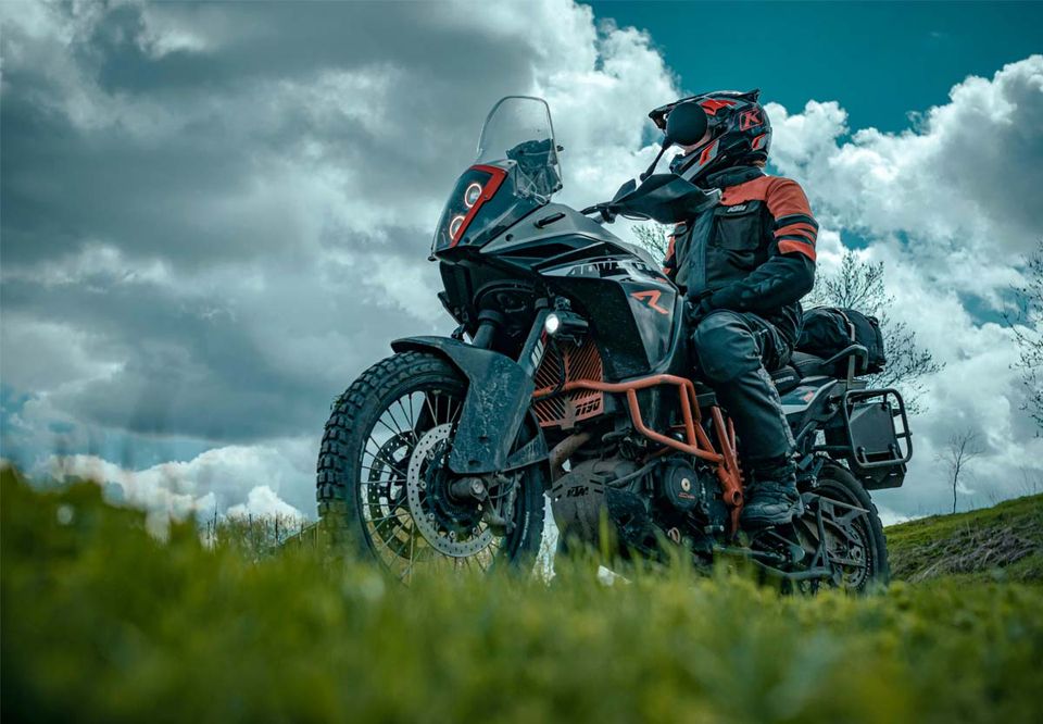 Two riders on loaded adventure bikes under a dramatic sky