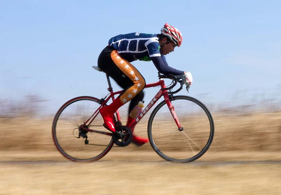 A cyclist in a tucked position sweeping past in motion blur