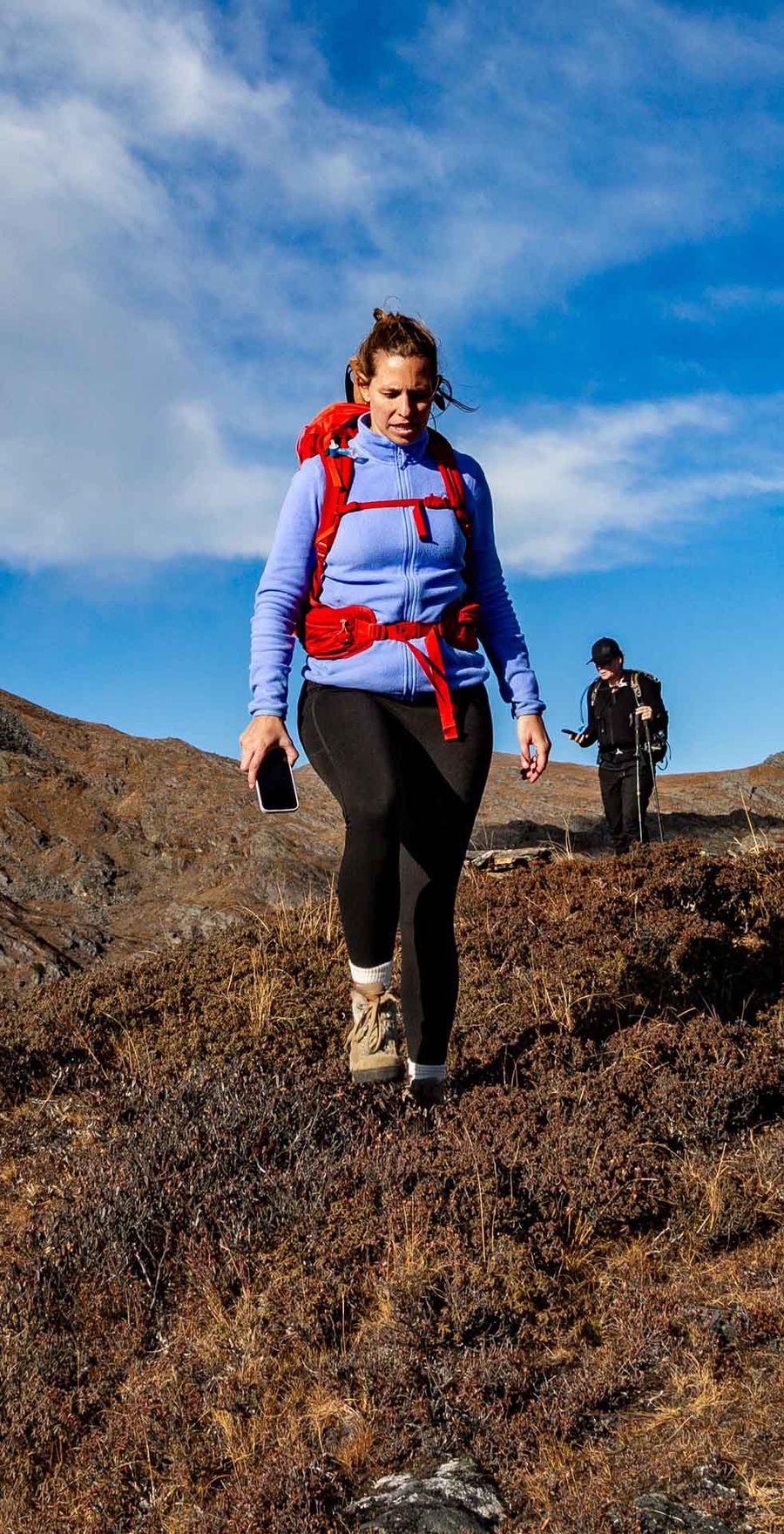A trekker descending an open ridge under a wide blue sky