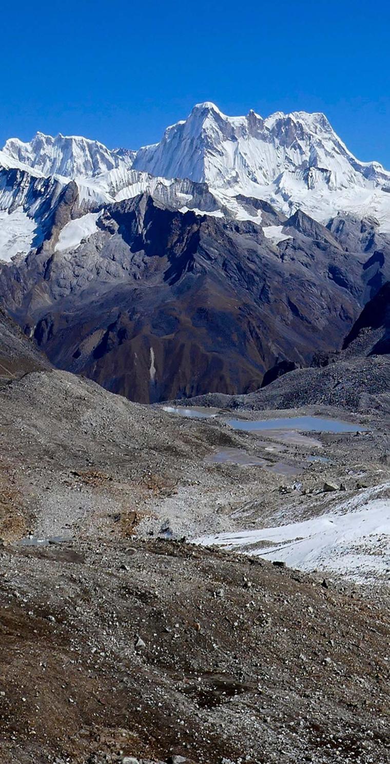 A broad snow-covered massif above a grey glacial moraine